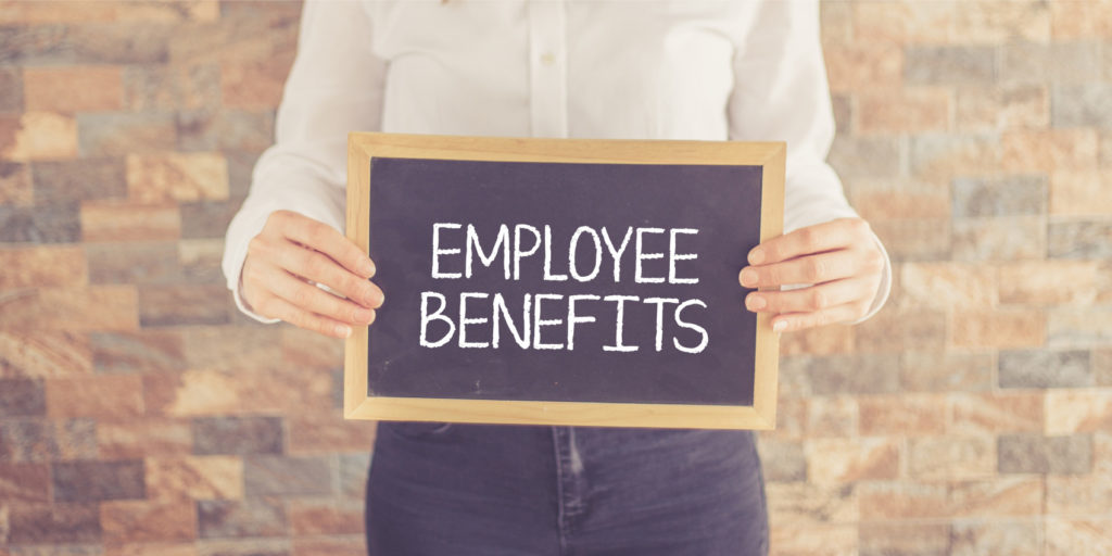 an employee of a company that has self-funded insurance holds a board with the text employee benefits