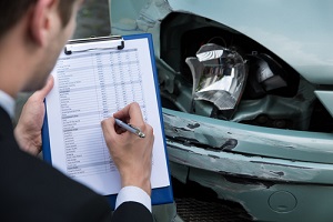 view of writing on clipboard while insurance agent examining car after accident