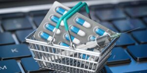 shopping basket with pills and syrringe on laptop keyboard