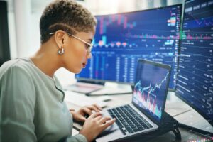 Laptop, investment graphs and business woman reading IPO analytics, financial bank chart or accounting value, info or stocks. Trade price, admin data analysis and profile of broker review statistics.